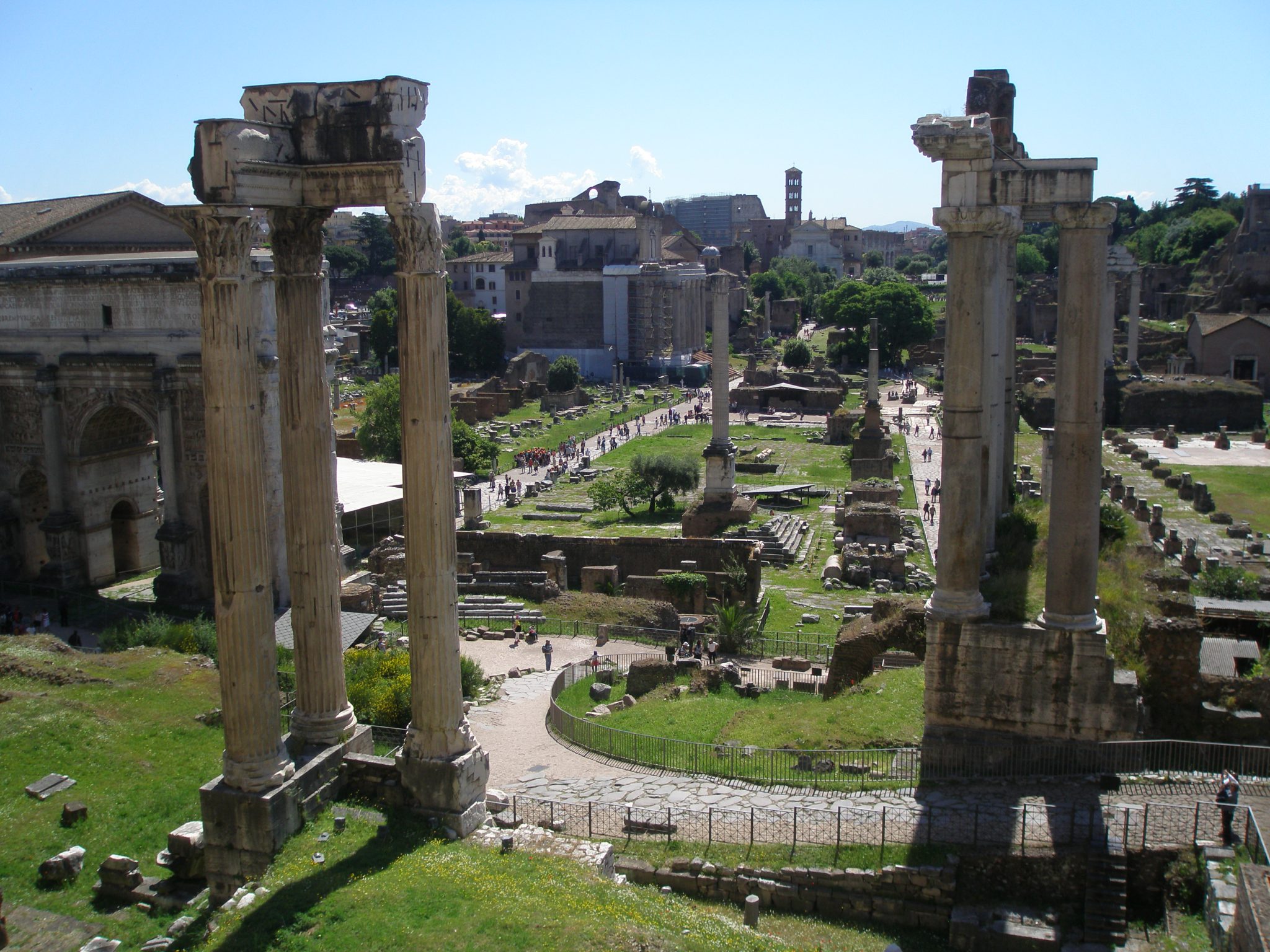 Another view from the Tabularium. Set back, in the center of the grassy rectangle are the Colonna di Foca (added in 609AD), & the Rostrum, which was a Speaker's Platform. The large green expanse marks the Square of the Roman Forum. To the left of the Forum, the long walkway is the Via Sacra. In the left foreground: 3 columns mark the corner of the Temple of Concord. In the right foreground, the tall columns and pediment are the front of the Temple of Saturn.