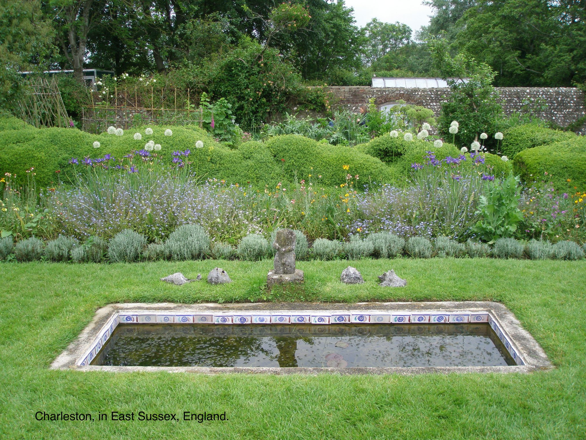 Charleston, East Sussex, England. A small pool at the center of the Walled Garden's lawn is edged with tiles that are reproductions of the original tiles, which were painted by Vanessa Bell in 1930.