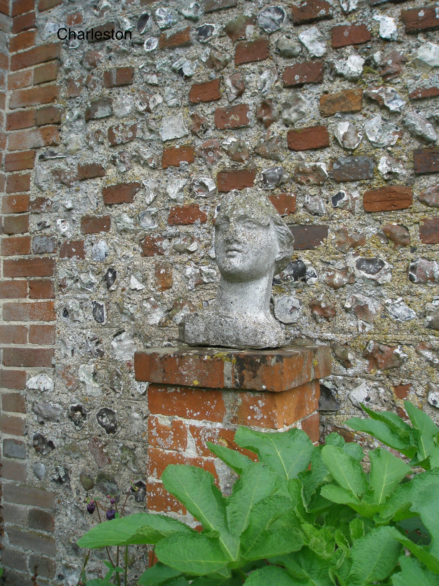 A Bust is mounted, just inside the entry to the Walled Garden. This wall is built with typical Southeastern England's combination of brick and broken flint stones.
