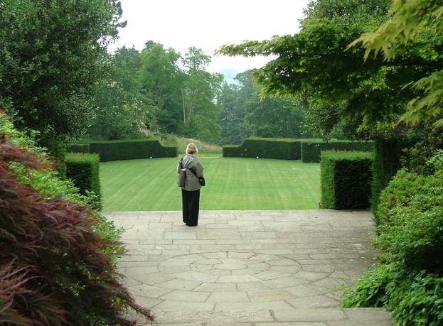 Nan, on the Terrace by the Swan Fountain, overlooks the Green of the Tiltyard. Part of the charm of the Tiltyard are the ways in which views of its precipitous slopes are often hidden, from other areas in Dartington's Gardens. Photo by Anne Guy.