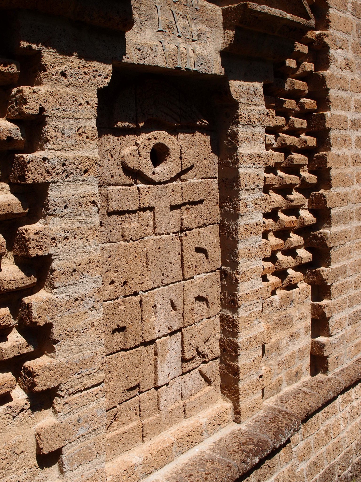 Walls usually have Ears. Buzzi’s walls have EYES. This City Wall detail shows how humble building materials—roughly-fashioned blocks and bricks---have been ingeniously assembled to form intricate, shadow-casting patterns. 